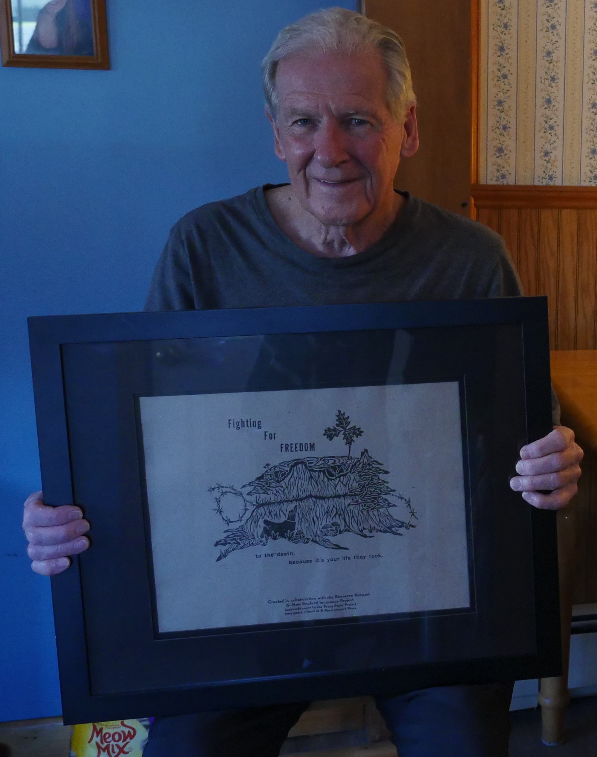 Paul Robinson in his kitchen holding a piece of art gifted to him by the New England Innocence Project